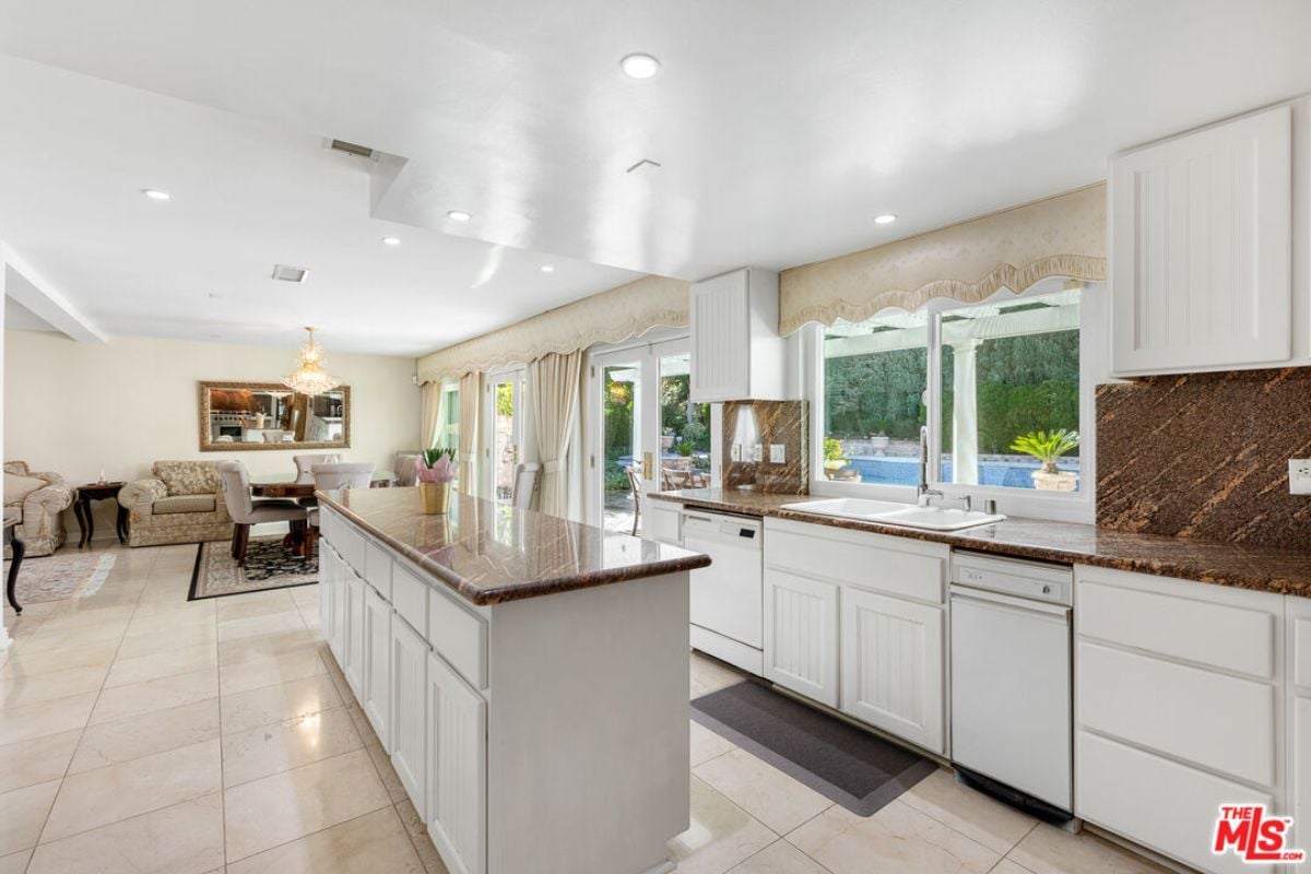 A kitchen with countertops, windows, sink, and cabinets.