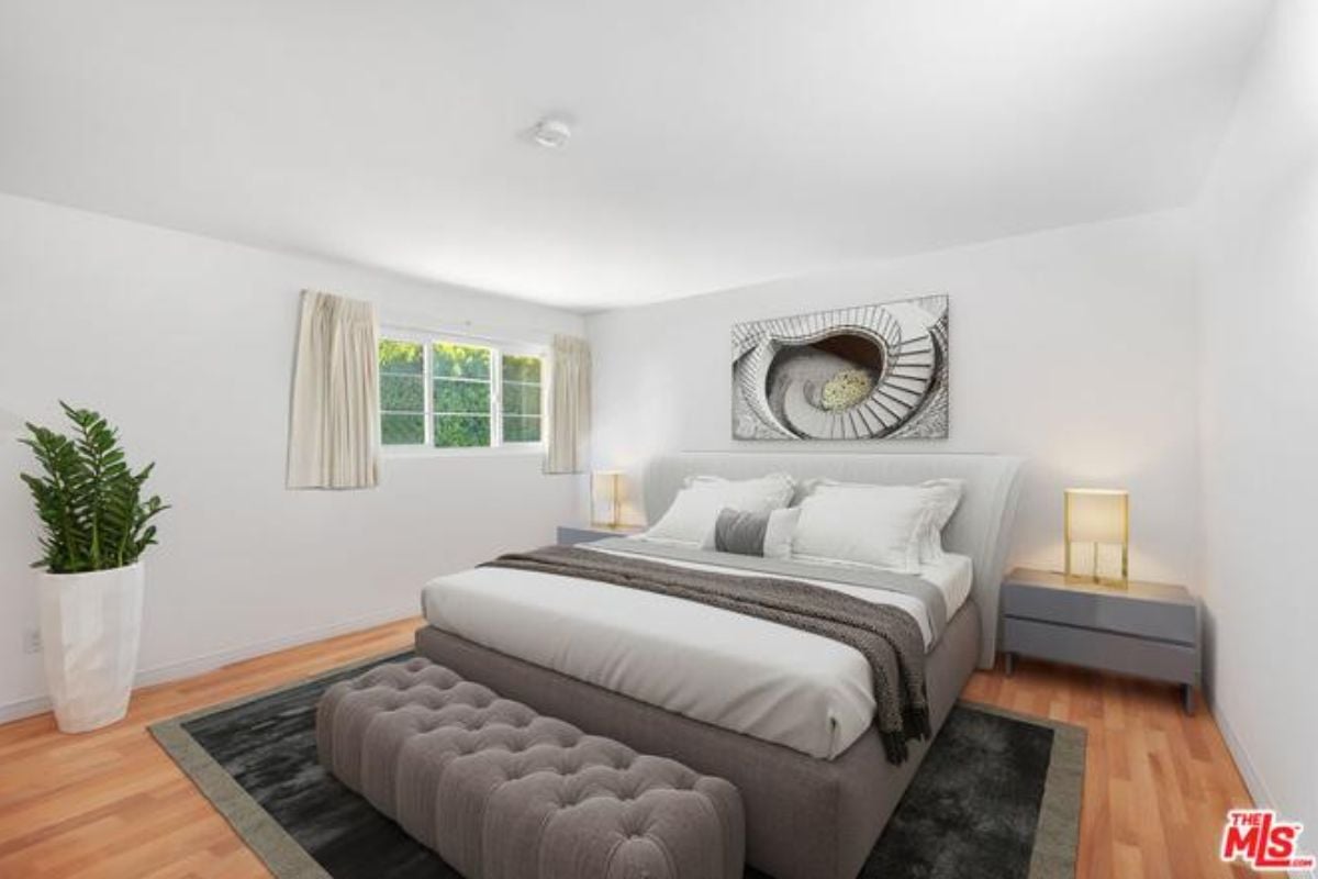 A bedroom with a bed, nightstand, window, painting, and vase.