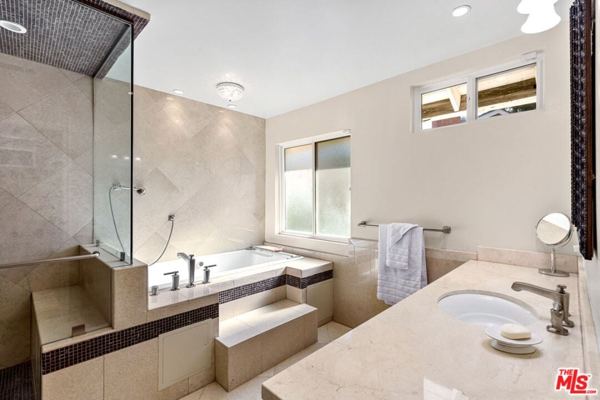 A bathroom with a tiled floor, countertop, tiled floor, sink, and shower room.