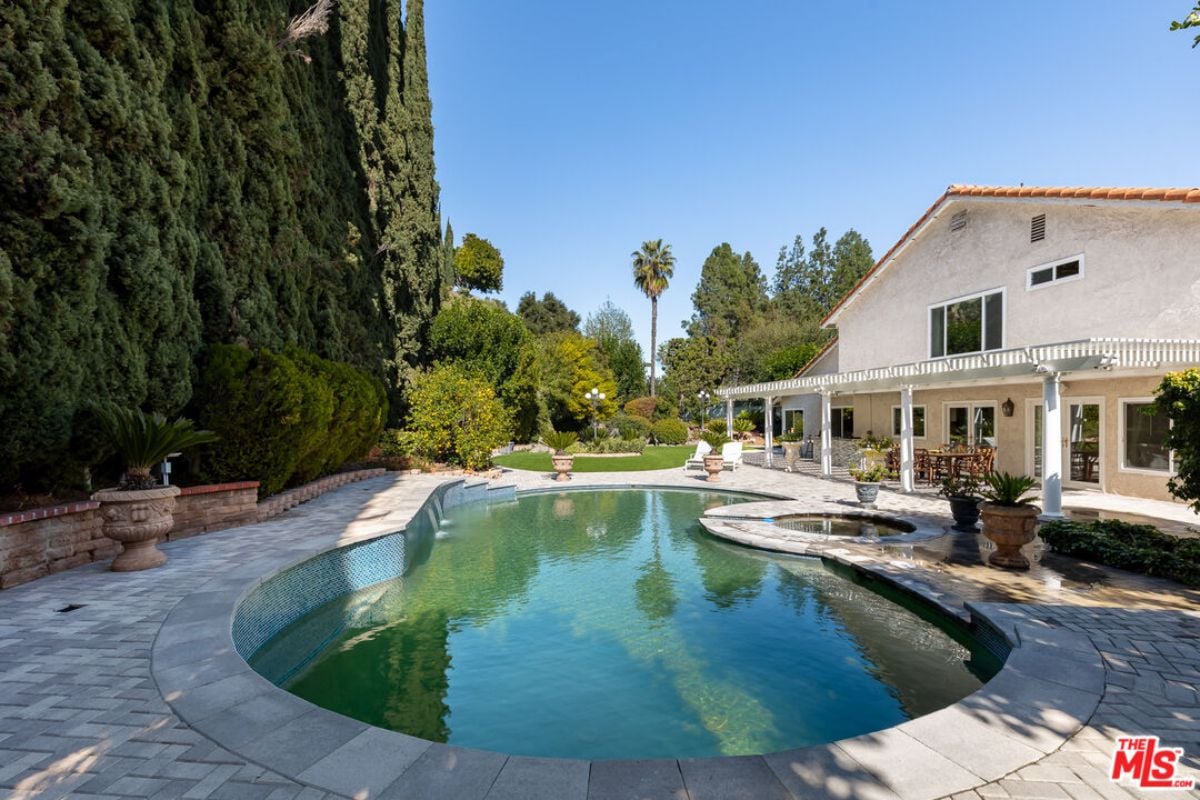 A swimming pool with a Jacuzzi surrounded by plants.