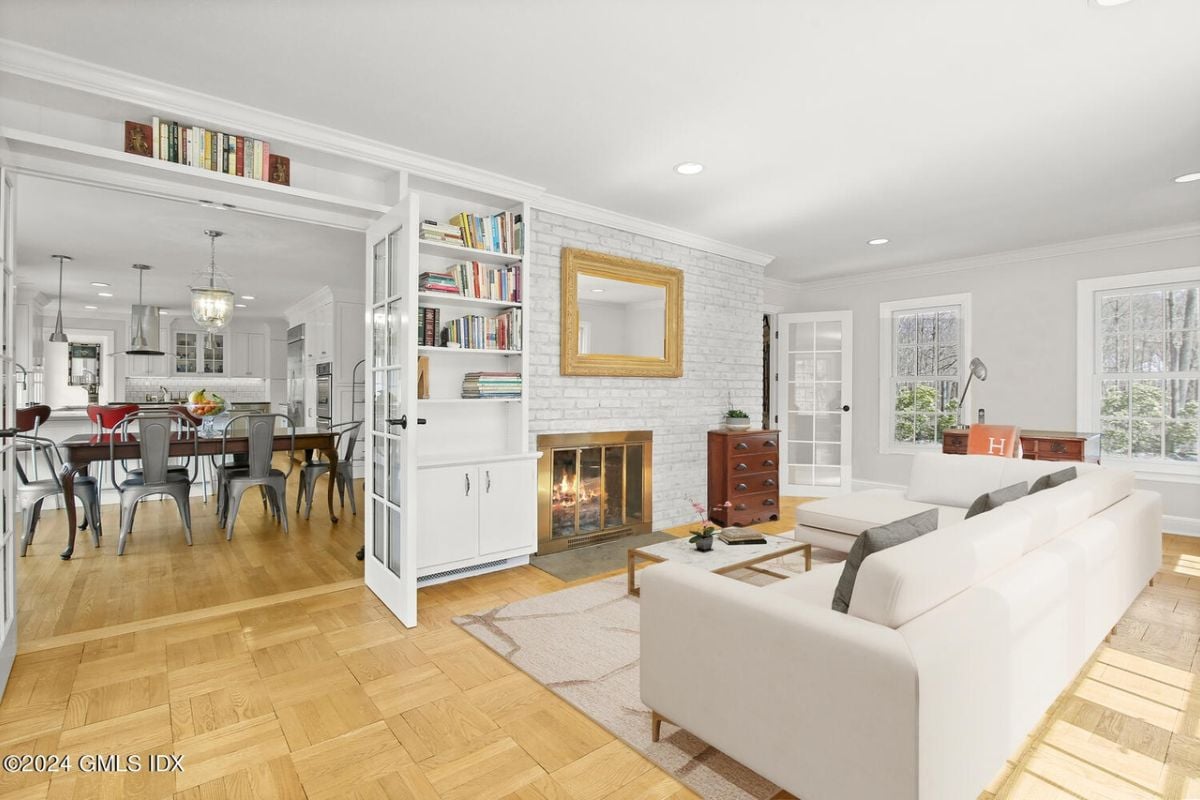 A living room with shelves, fireplace, painting, cabinet, couch, and center table.