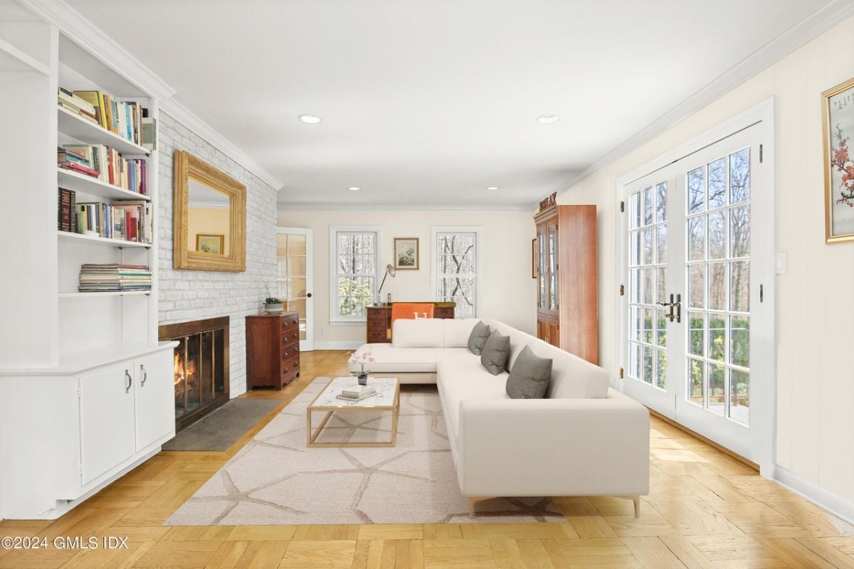 A living room with shelves, fireplace, painting, cabinet, couch, and center table.