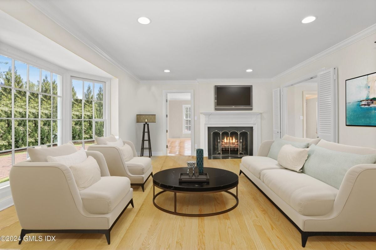 A living room featuring a fireplace, TV, windows, round center table, and couches.
