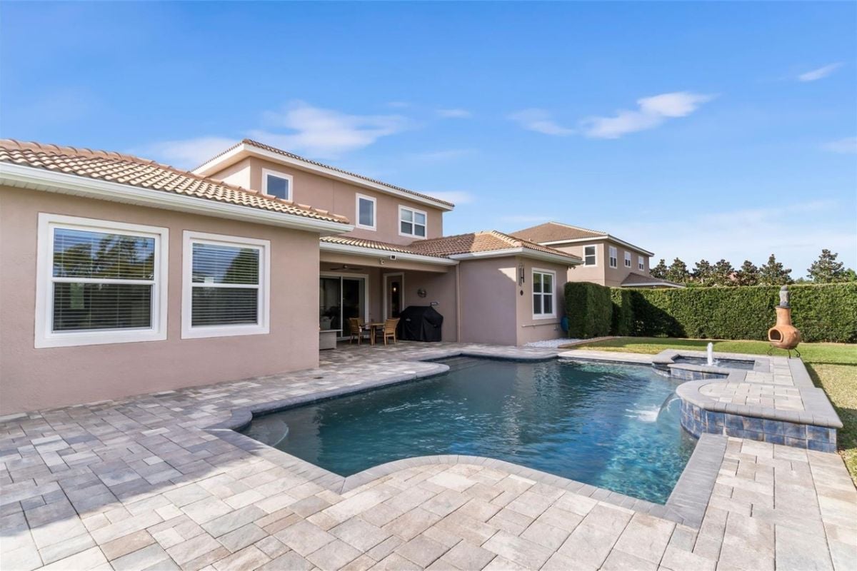 A swimming pool and jacuzzi with a brick poolside.