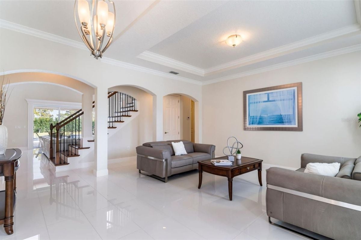 A living room with a painting, chandelier, gray couches, and a center table.