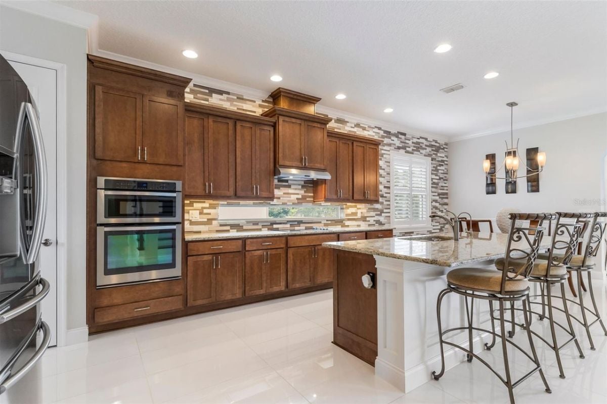 A kitchen with countertops, stools, cabinets, and kitchen appliances.
