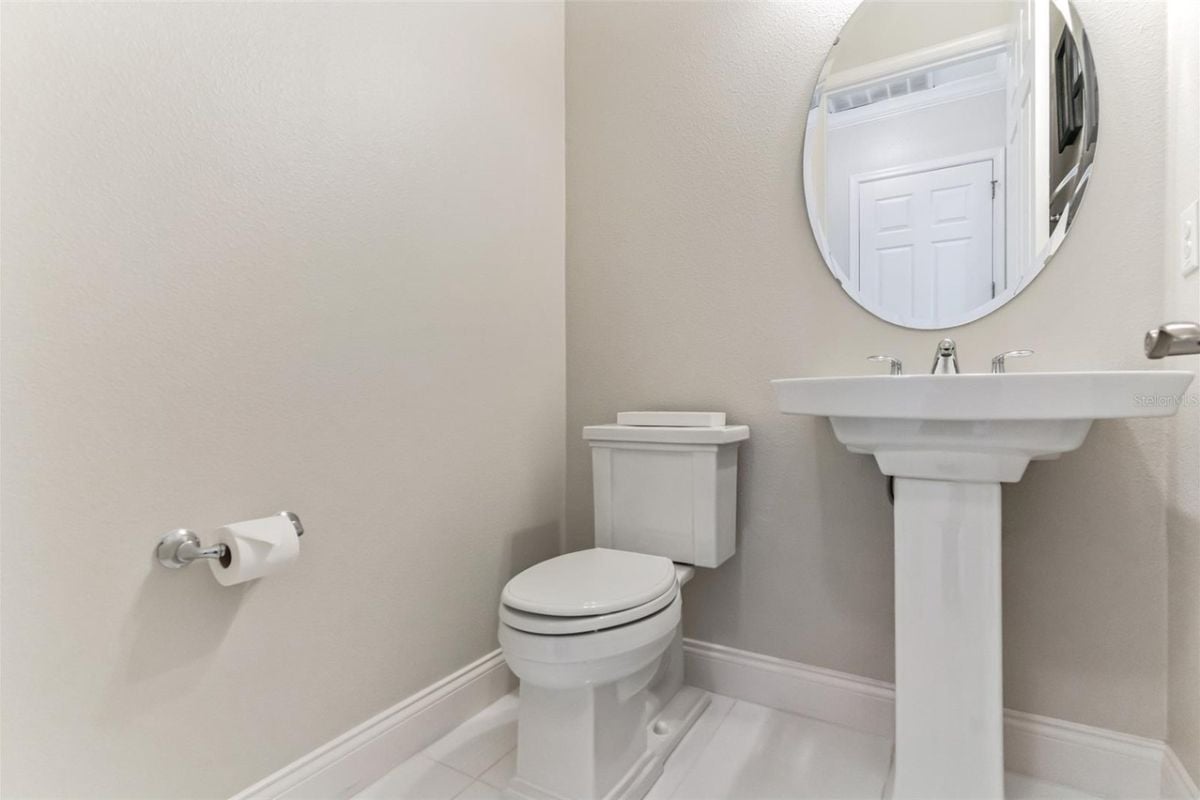 A bathroom with a vanity, mirror, and toilet.