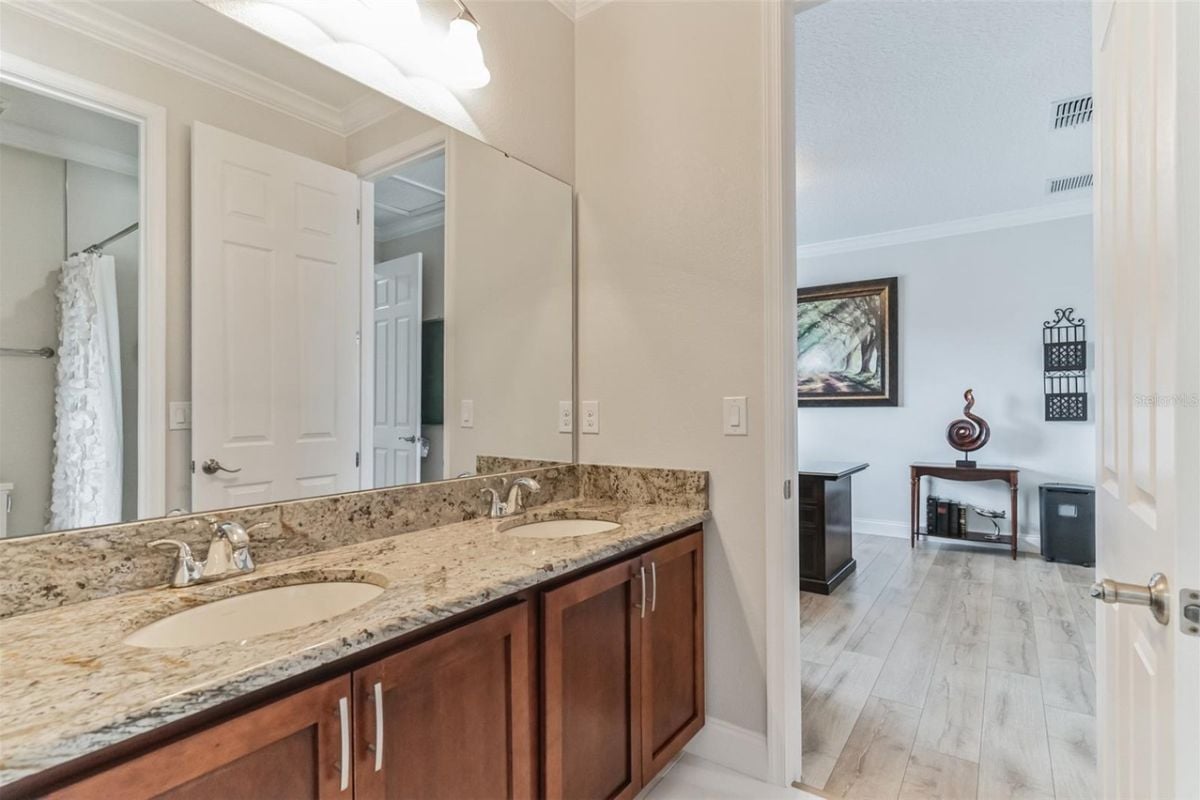 A bathroom with dual vanities, cabinets, and a mirror.