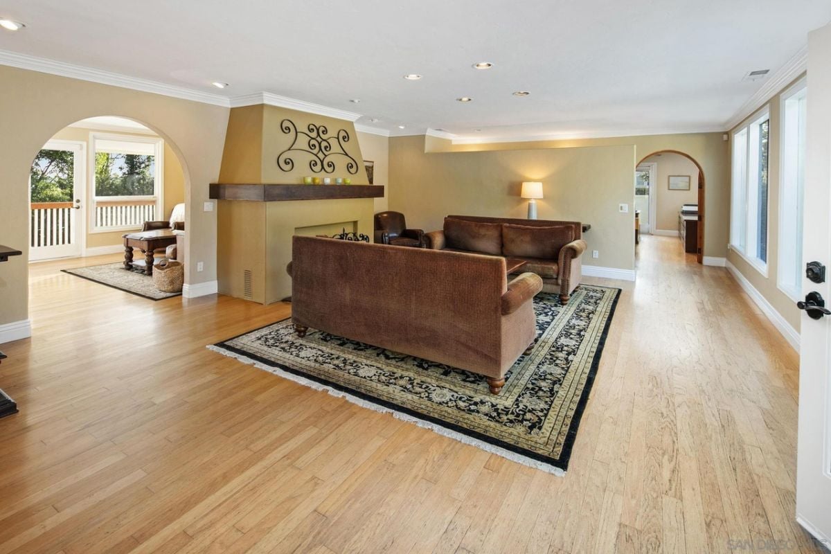 A living room with a fireplace, rug, and brown couches.