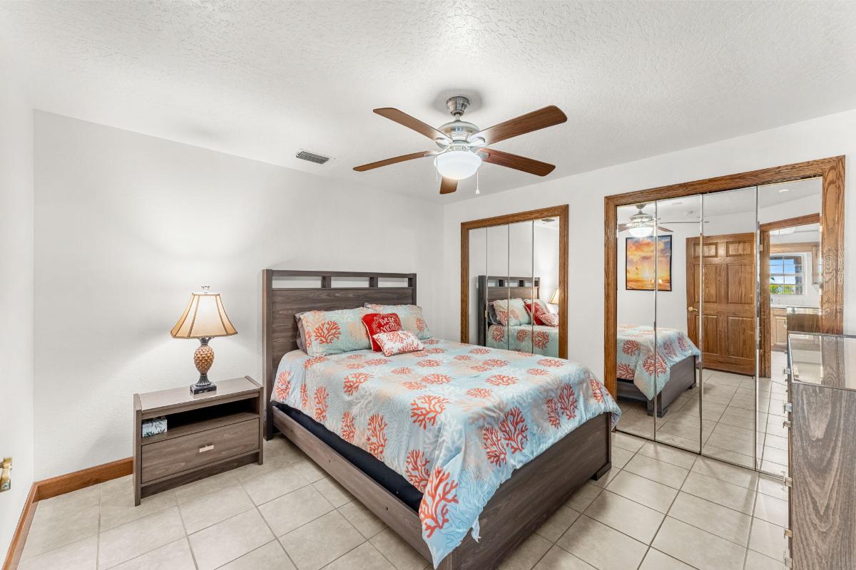 Bedroom with tile flooring and large mirrors.