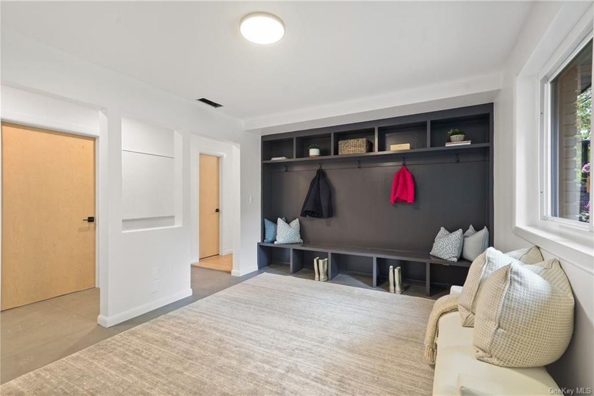 A mudroom with a bench, shelf, couch, and window.