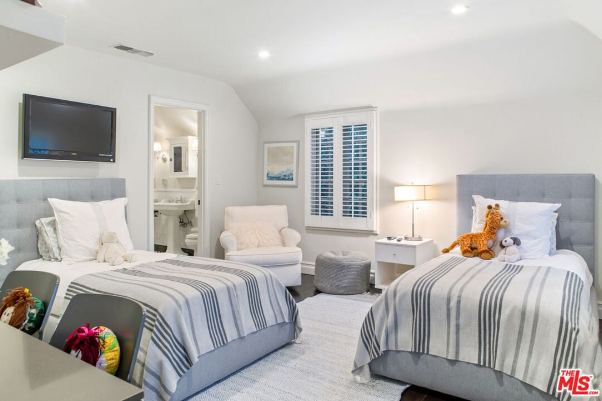 A kid's bedroom with two beds, a studio couch, a window, a TV, and a nightstand.