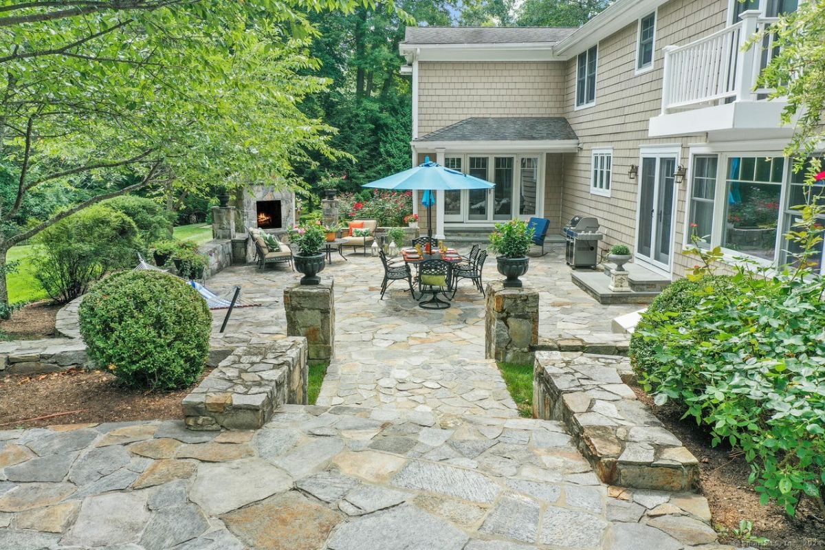 A patio with a fireplace, a table with an umbrella and chairs, and plants.