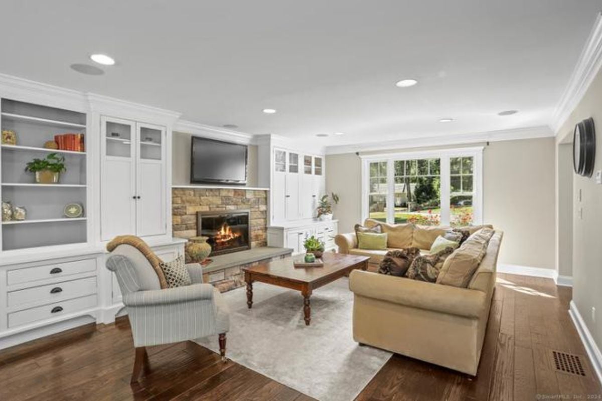 A living room with a shelf, cabinet, fireplace, TV, rug, couches, and a center table.