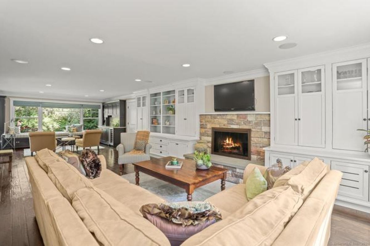 A living room with a shelf, cabinet, fireplace, TV, rug, couches, and a center table.