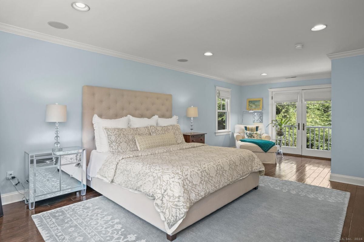 A bedroom with a bed, nightstand, rug, studio couch, and blue walls.