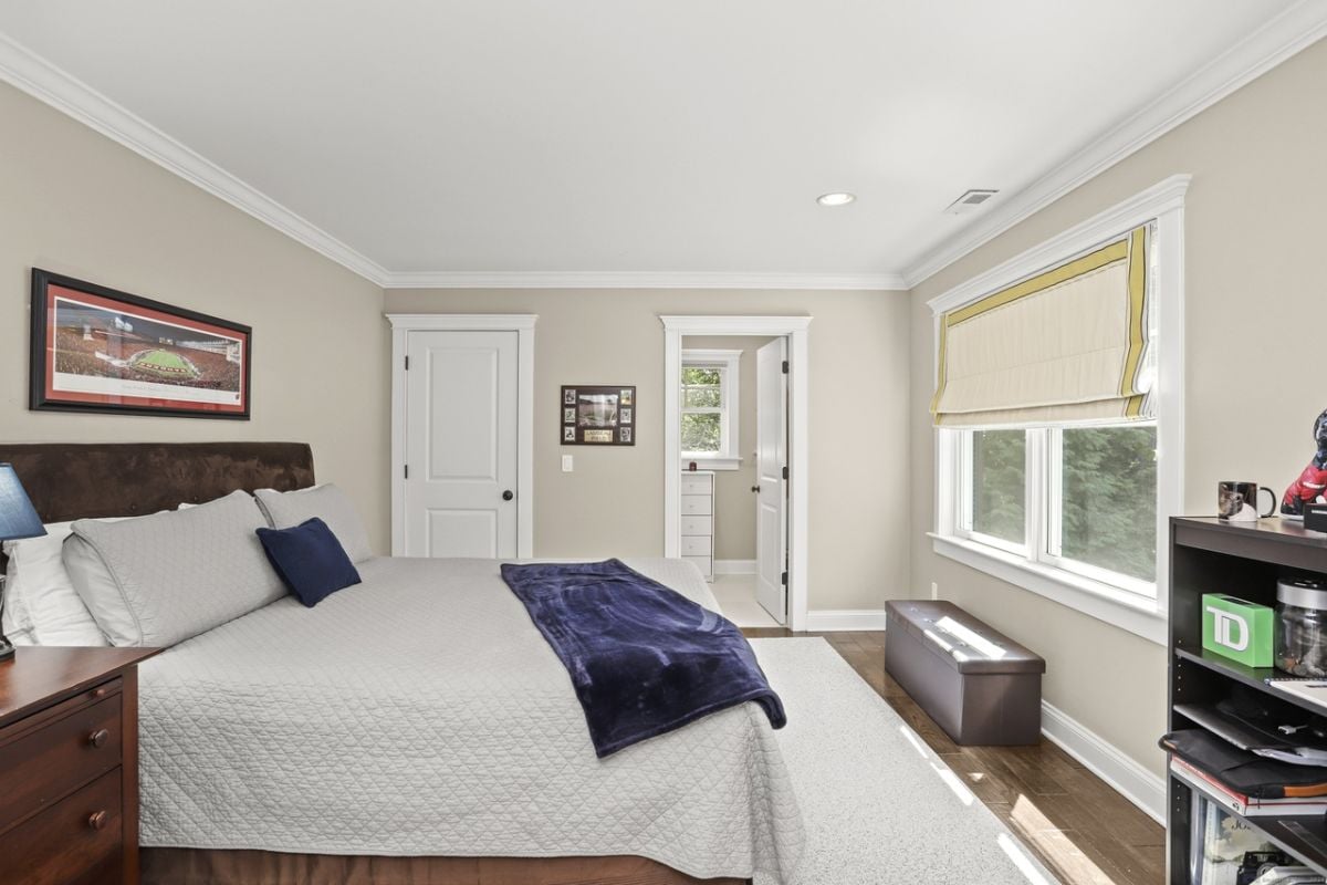 A bedroom with a bed, nightstand, window, and window seating.