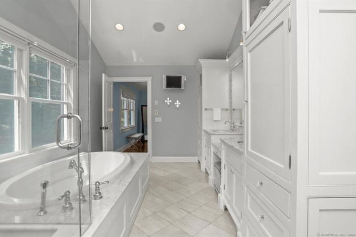 A bathroom with tiled floors, cabinets, and a bathtub.