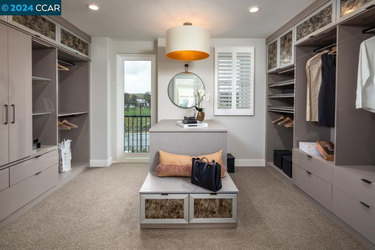 A walk-in closet with a center island, cabinets, and drawers.