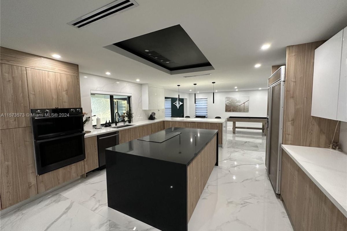 A kitchen with a tiled floor, center island, countertops, cabinets, and kitchen appliances.