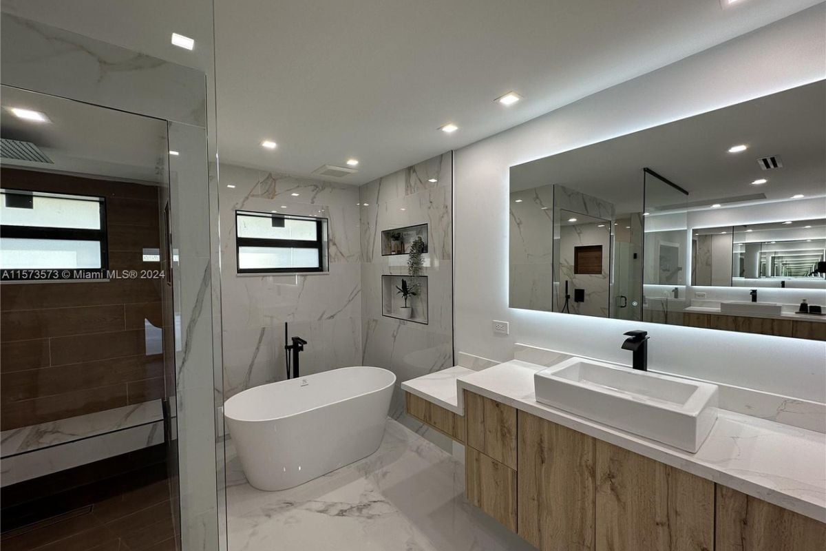 A bathroom with a vanity, mirror, cabinets, shower room, and bathtub.