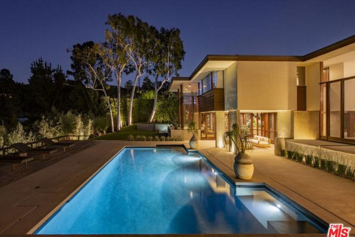 A swimming pool surrounded by potted plants, bushes, and trees.