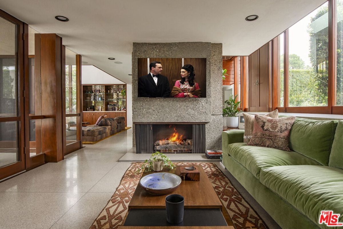 A living room with a TV, fireplace, rug, couch, and center table.