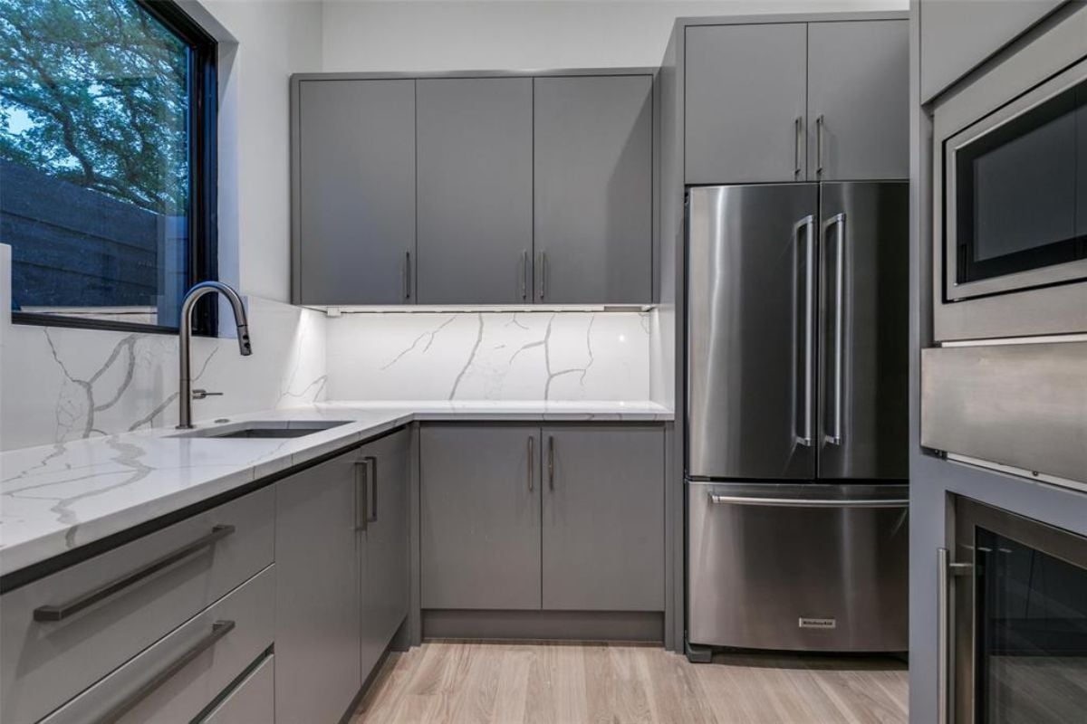A kitchen with a countertop, sink, cabinets, and kitchen appliances.