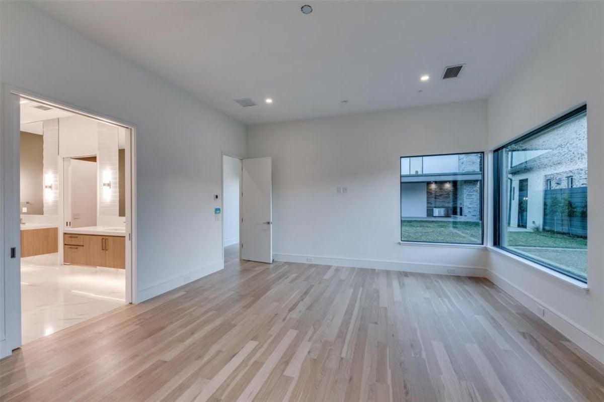 An empty room with wooden floors and windows.