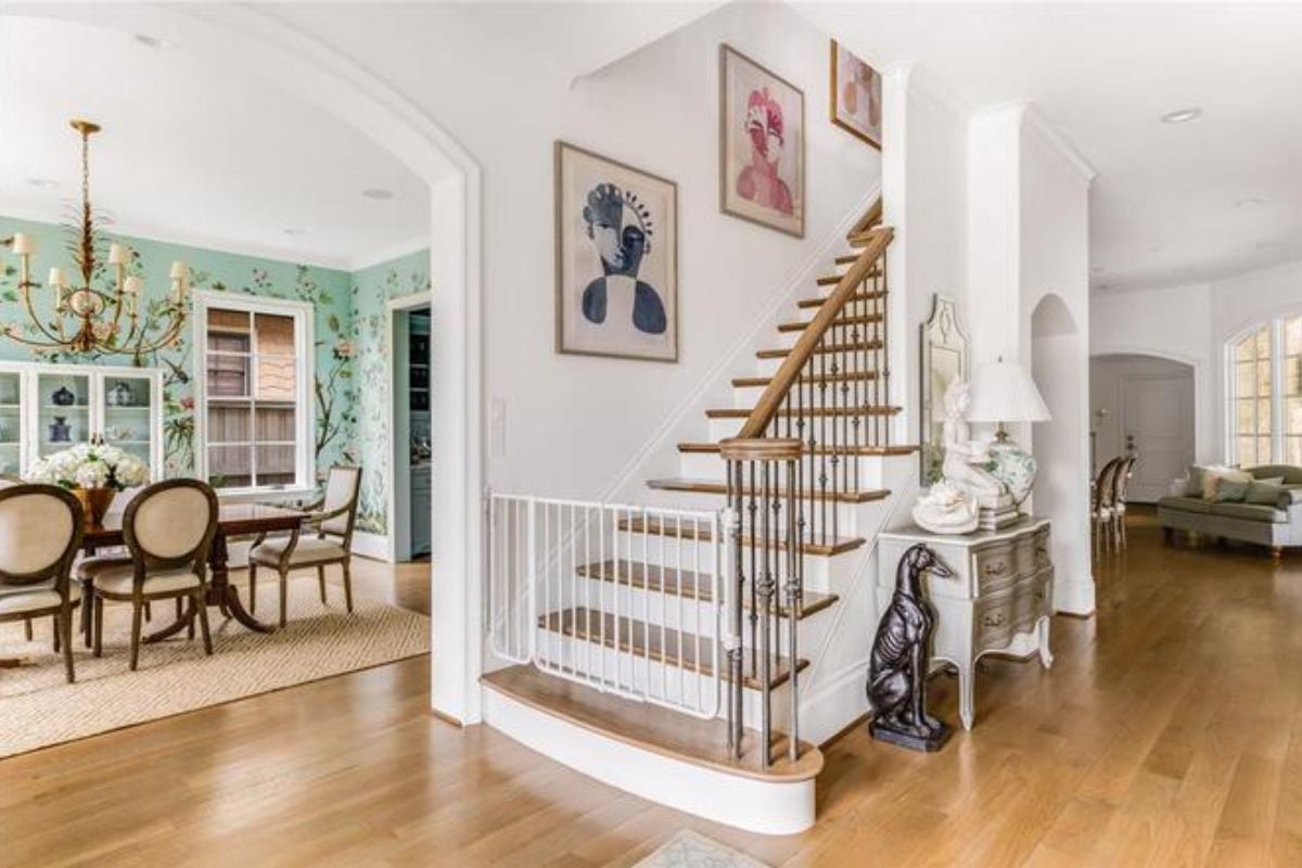 A foyer with a wooden floor, cabinet, and staircase.