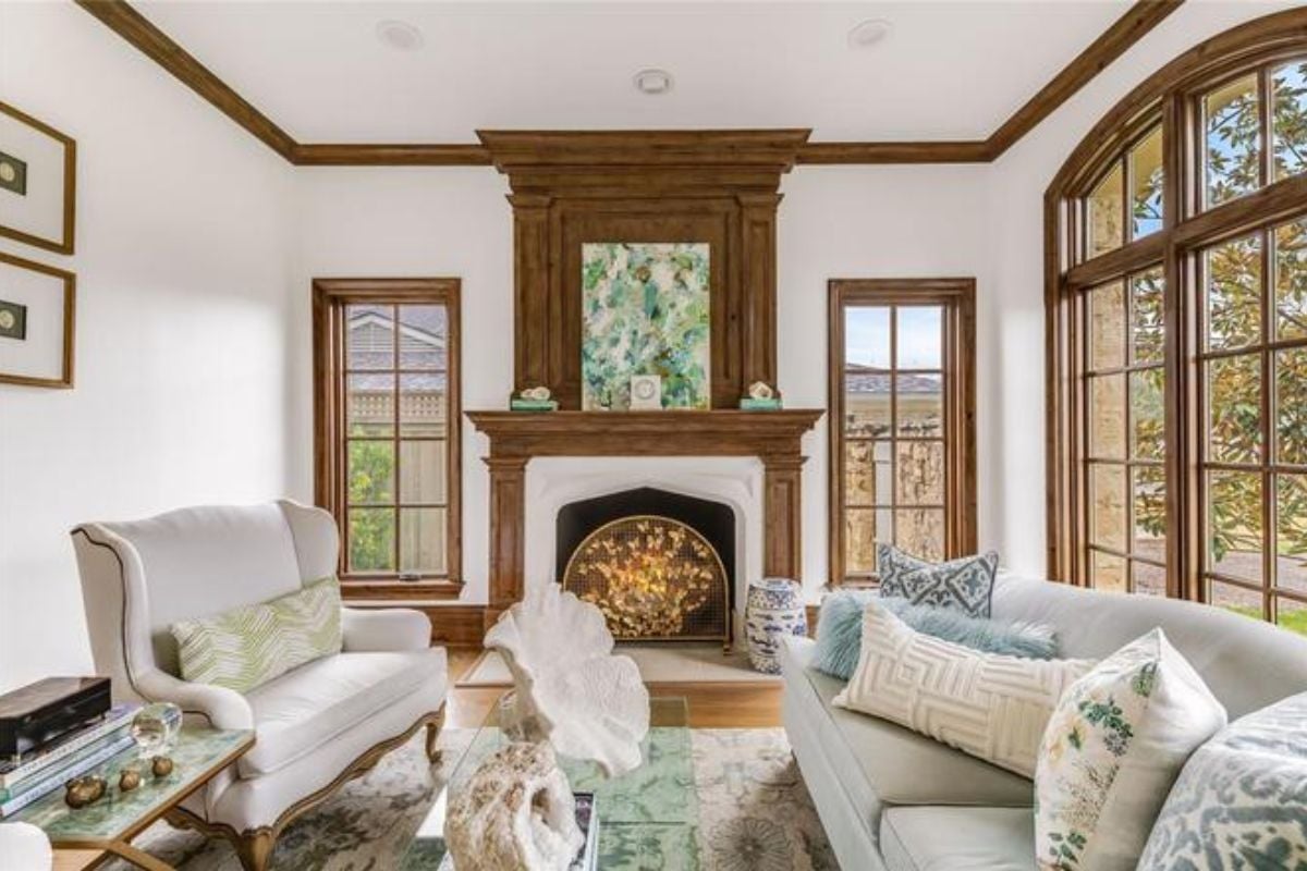 A living room with a fireplace, windows, couches, and a glass center table.