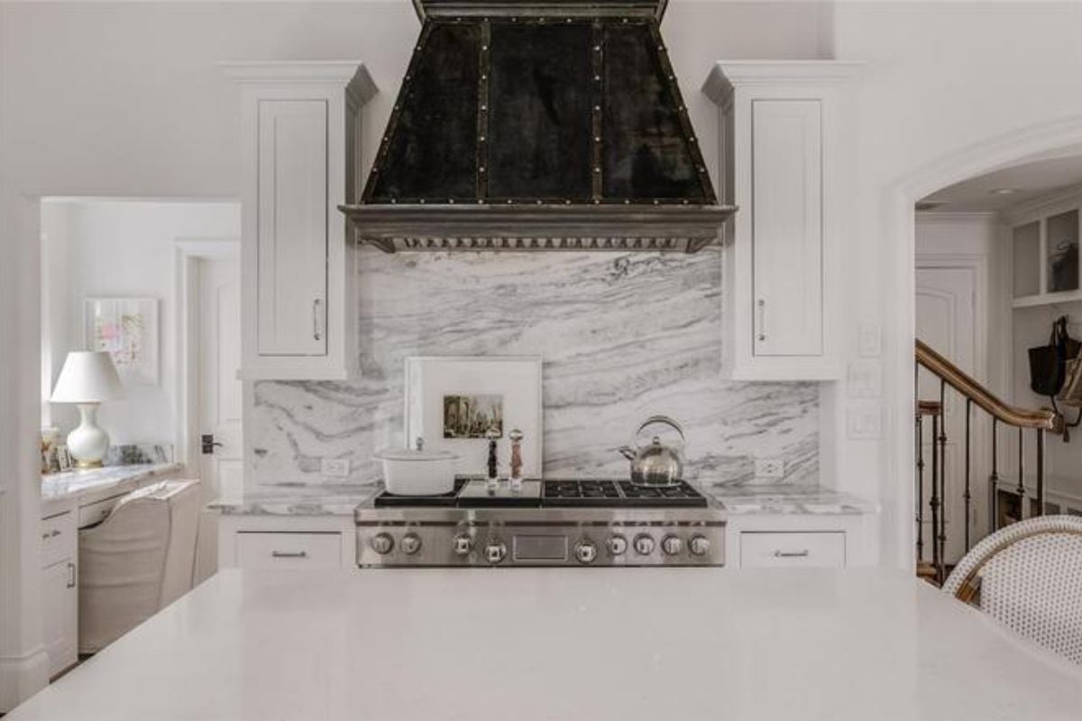 A kitchen with an island, countertop, stove, and cabinets.