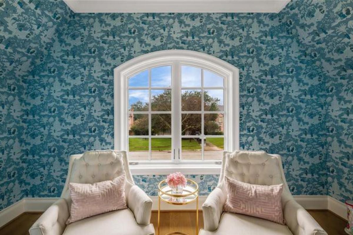 A seating area with wallpaper, a window, and chairs.