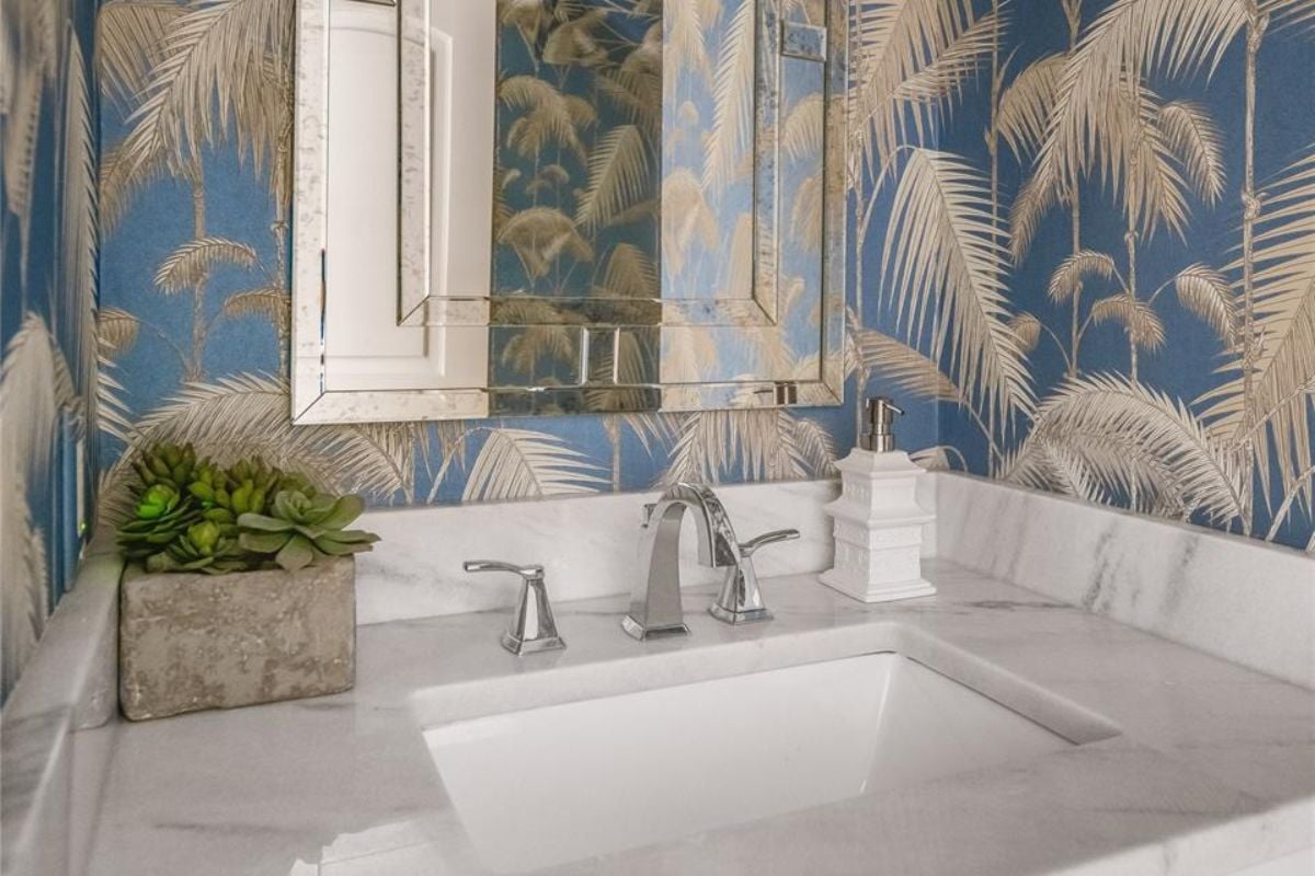 A bathroom with wallpaper and a vanity.