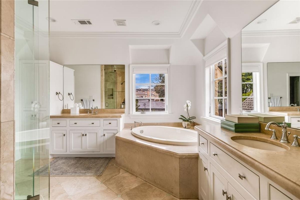 A bathroom with a vanity, mirror, countertop, sink, cabinets, and bathtub.