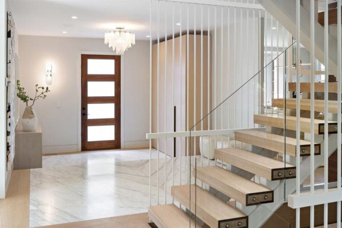 A foyer with a tiled floor, chandelier, case, and staircase.