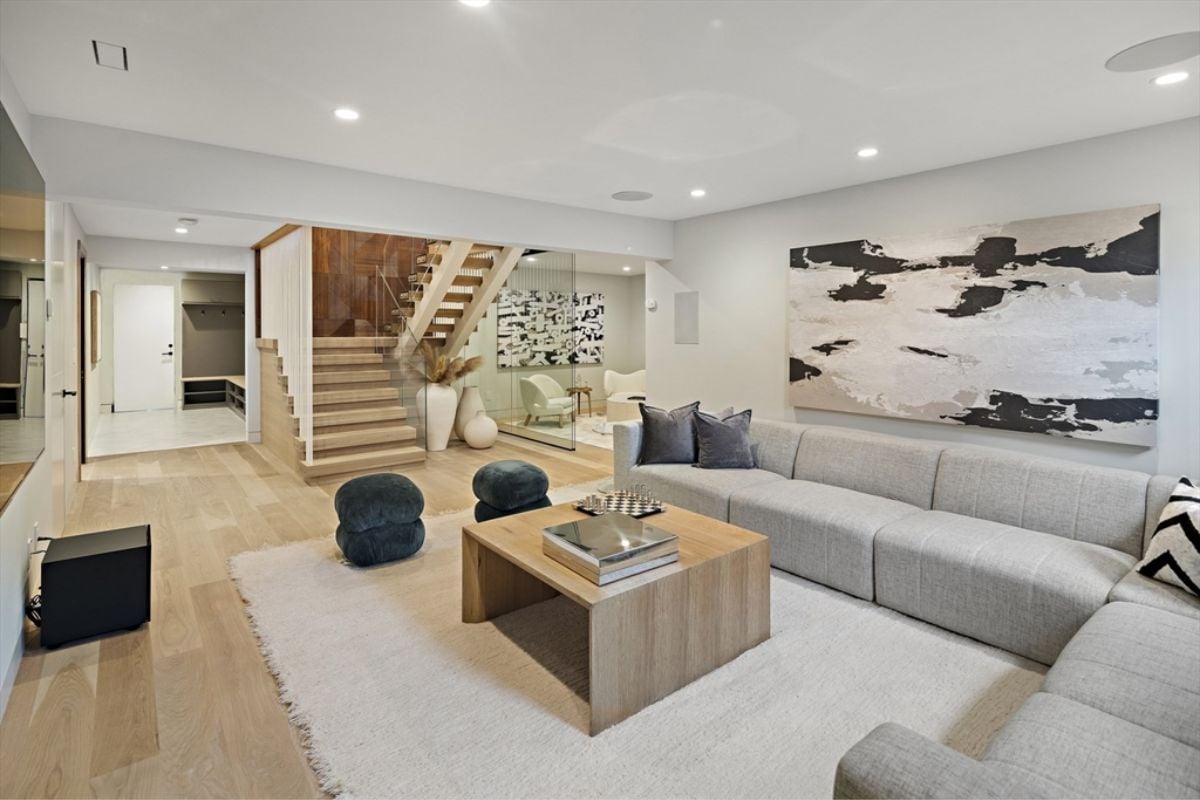 A living room with a painting, TV, couch, chairs, and a center table.