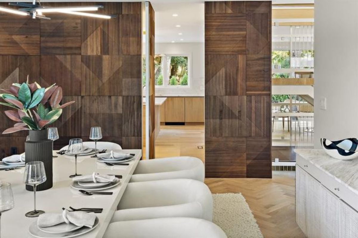A dining room with a dining table adorned with a vase and surrounded by chairs.