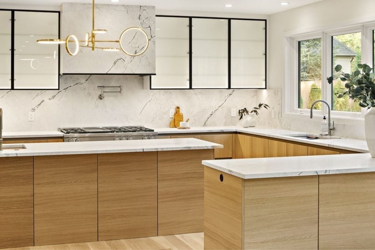 A kitchen with a center island, sink, countertops, stove, and cabinets.