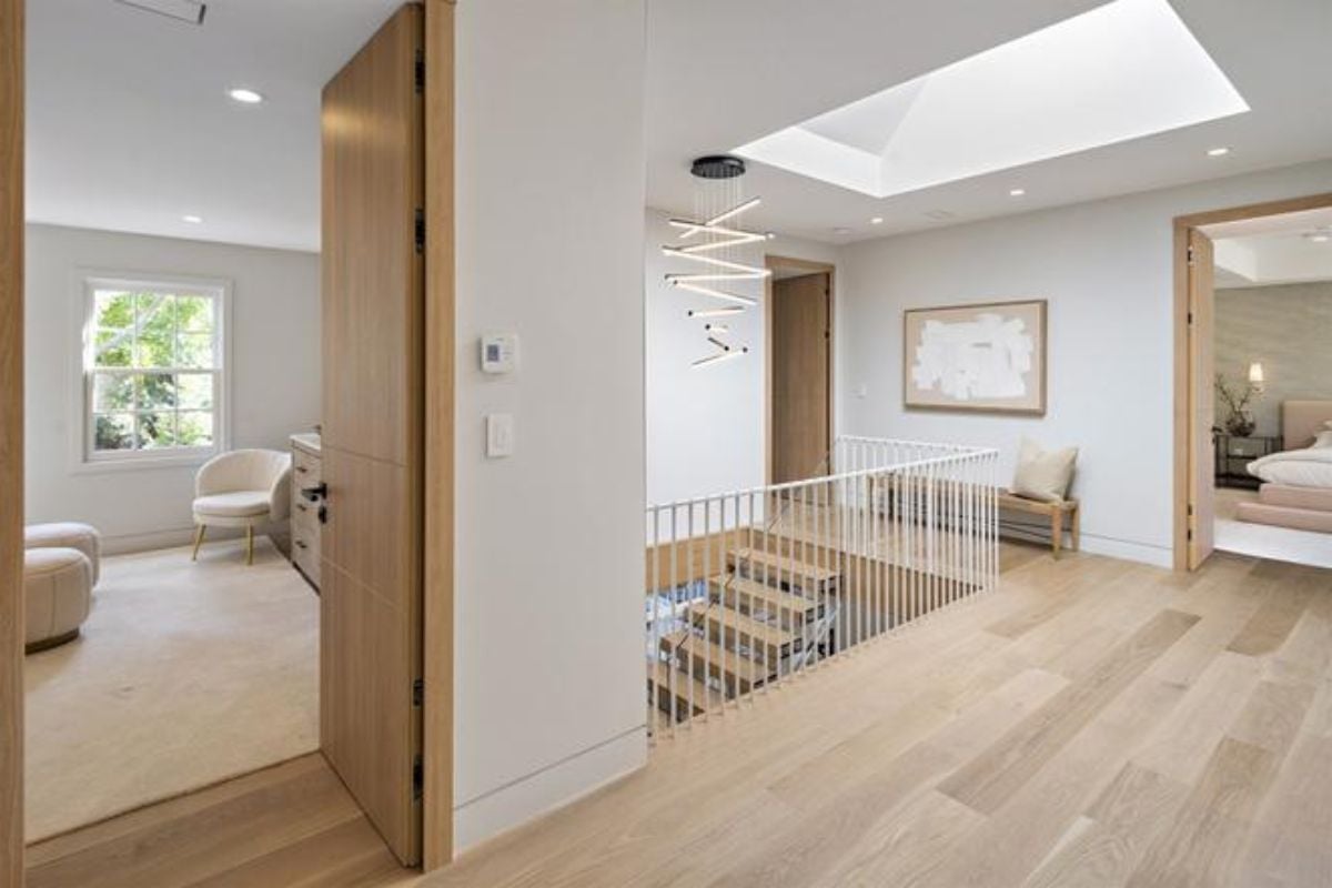 A landing with wooden floors, a bench, a skylight ceiling, and a metal handrail.
