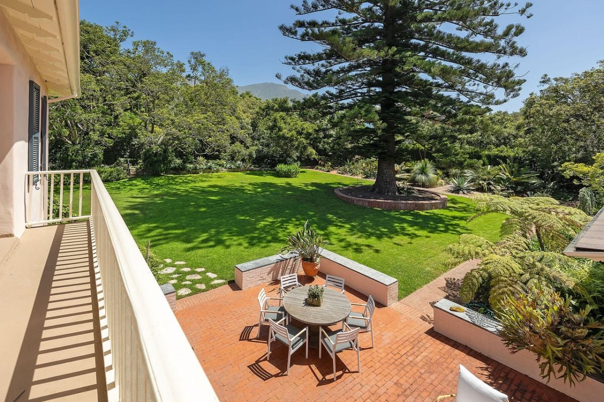 There is a porch with a table surrounded by chairs.