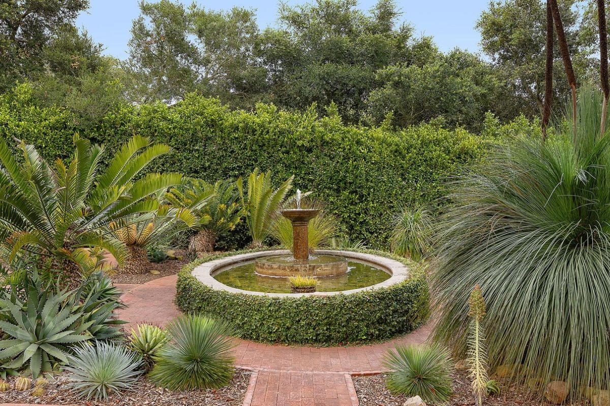 There is a garden with a fountain surrounded by plants.