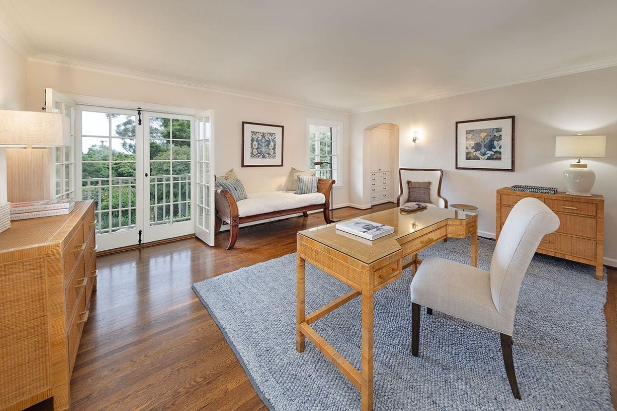 A home office with couch, cabinets, rug, desk, and chairs.