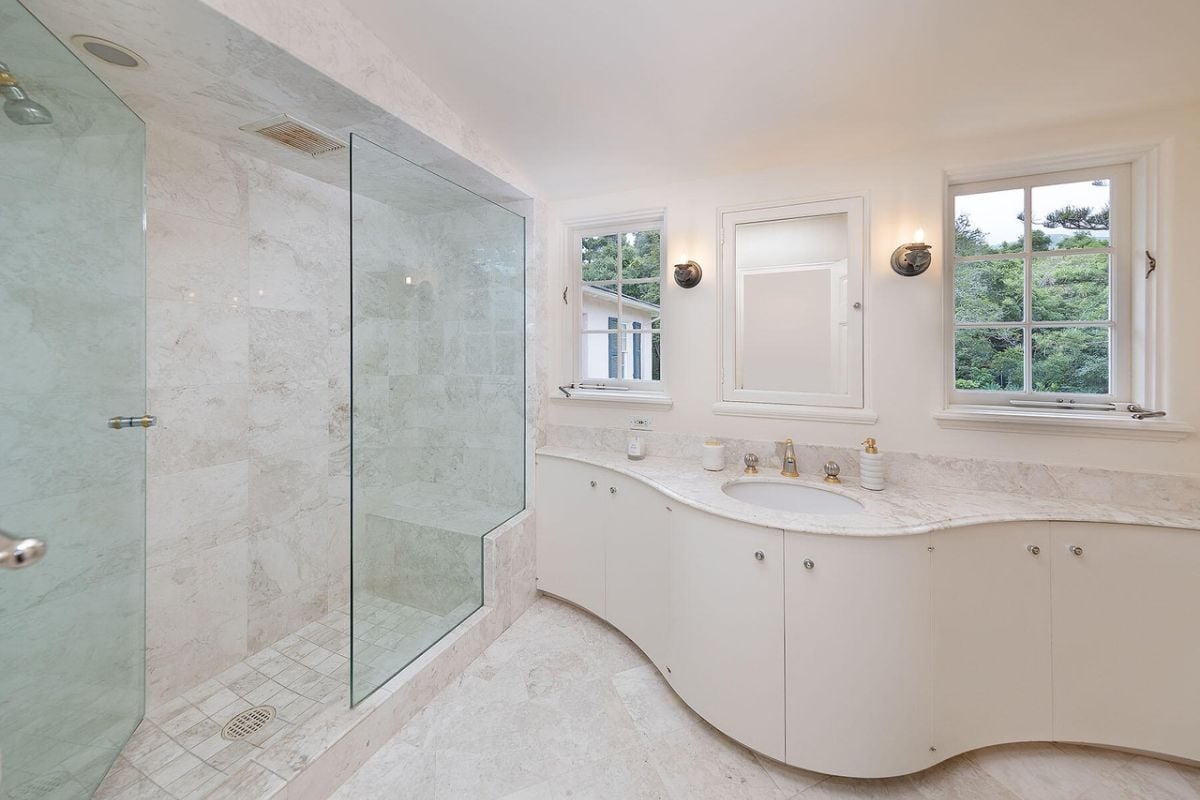 A bathroom with windows, a vanity, and a shower room.