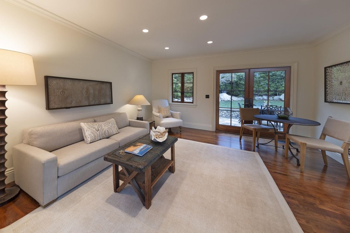 A living room with a couch, rug, table, window, and chairs.