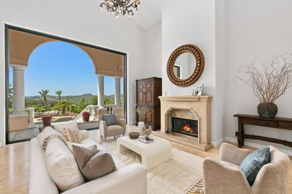 A living room with a fireplace, couches, chairs, a center table, and a chandelier.