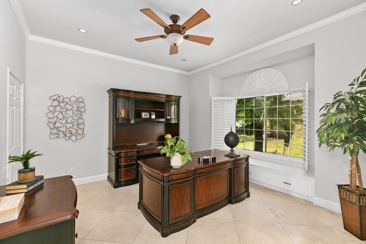 A home office with a ceiling fan, cabinets, a window, a houseplant, and a desk.
