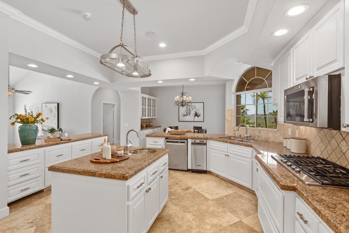 A kitchen with countertops, a center island, a sink, cabinets, and kitchen appliances.