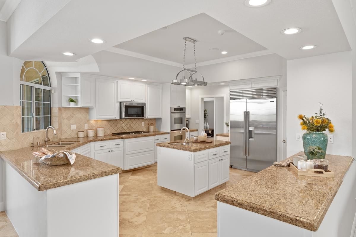 A kitchen with countertops, a center island, a sink, cabinets, and kitchen appliances.