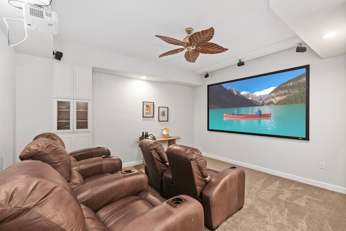 A home theater with a ceiling fan, a large screen, and chairs.